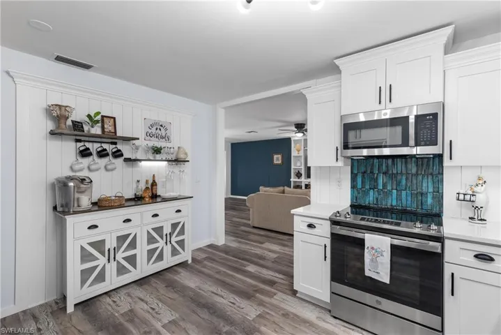 Kitchen with appliances with stainless steel finishes, open shelves, and white cabinetry