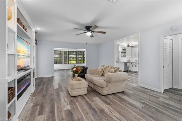 Living room featuring wood finished floors, a ceiling fan, a glass covered fireplace, and recessed lighting