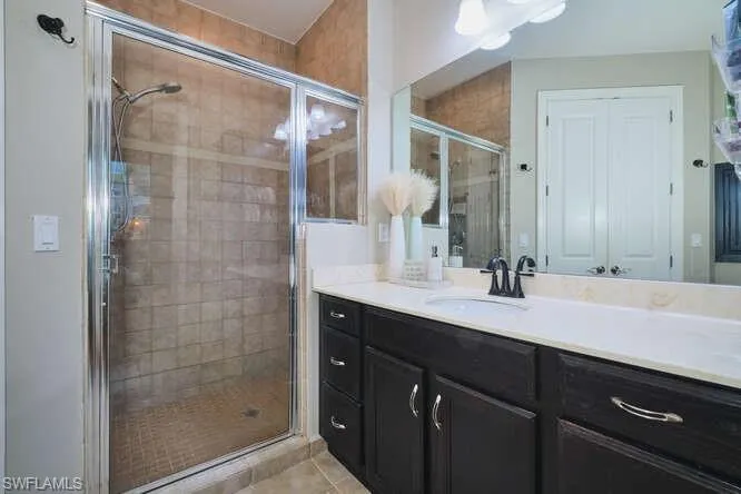 Full bath featuring vanity, a stall shower, and light tile patterned floors