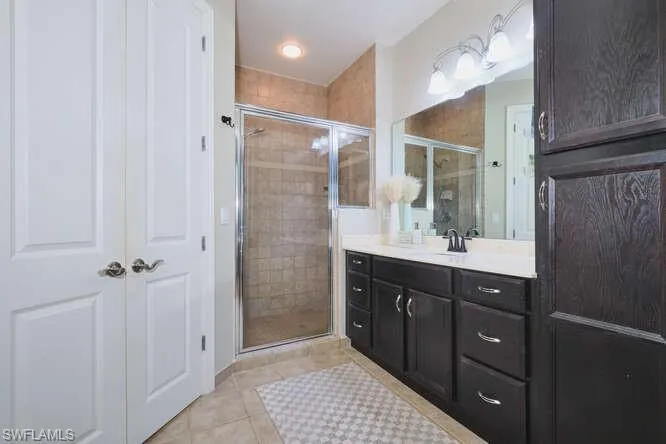 Bathroom featuring vanity, a shower stall, and light tile patterned floors