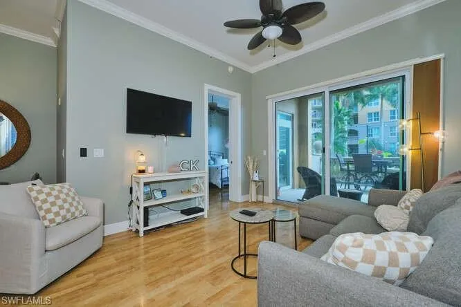 Living room with light wood-style flooring, ceiling fan, and crown molding