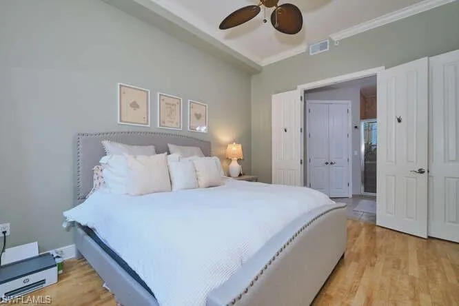 Bedroom featuring light wood finished floors, a ceiling fan, and crown molding