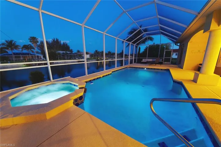 View of swimming pool featuring a water view, a patio area, a lanai, and a pool with connected hot tub