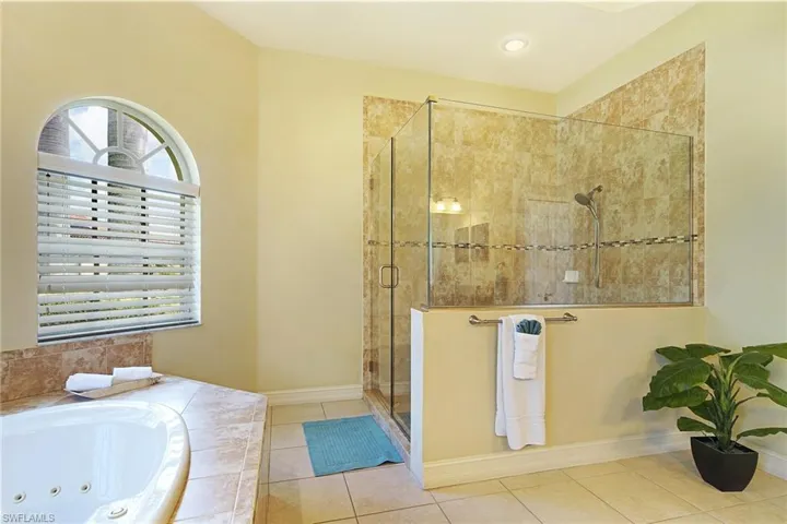 Bathroom featuring a stall shower, a jetted tub, and tile patterned floors