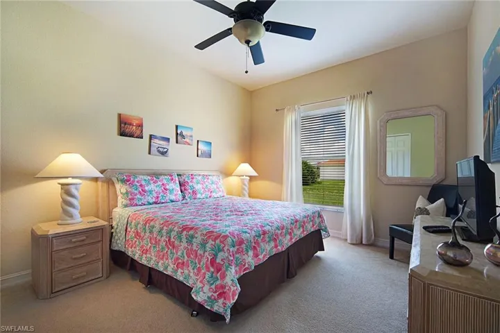 Bedroom featuring light colored carpet, baseboards, and a ceiling fan