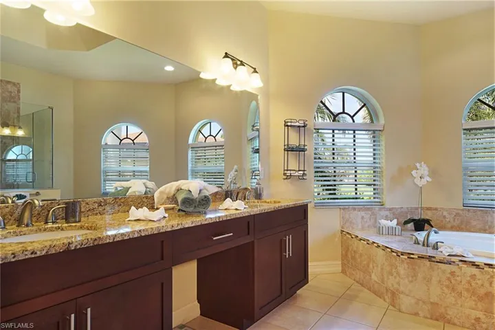Bathroom featuring healthy amount of natural light, tile patterned flooring, a bath, and double vanity