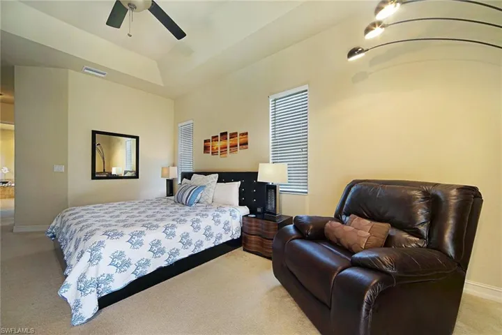 Bedroom with light colored carpet, baseboards, and a ceiling fan