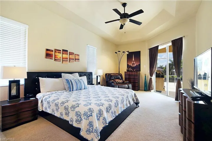 Carpeted bedroom featuring access to exterior, a ceiling fan, and a raised ceiling