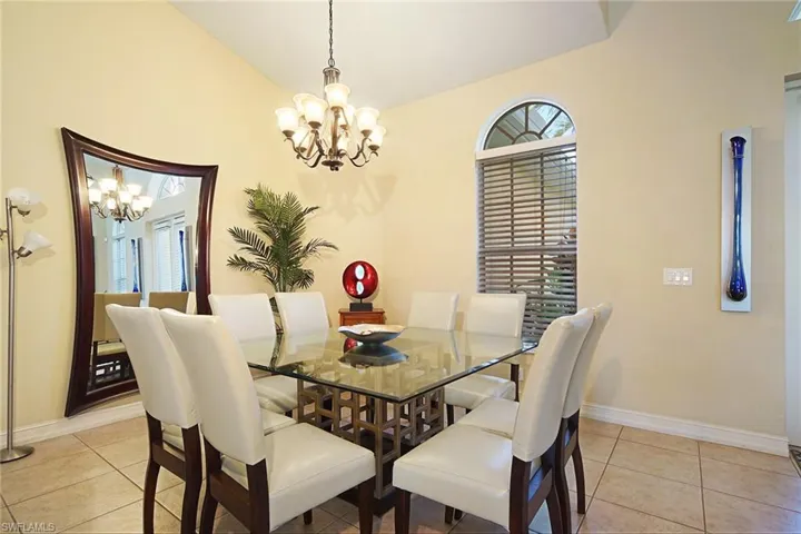 Dining space featuring a chandelier, baseboards, light tile patterned floors, and vaulted ceiling