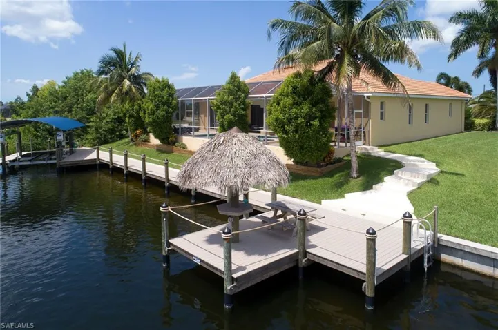 Dock featuring a water view, a yard, and a lanai