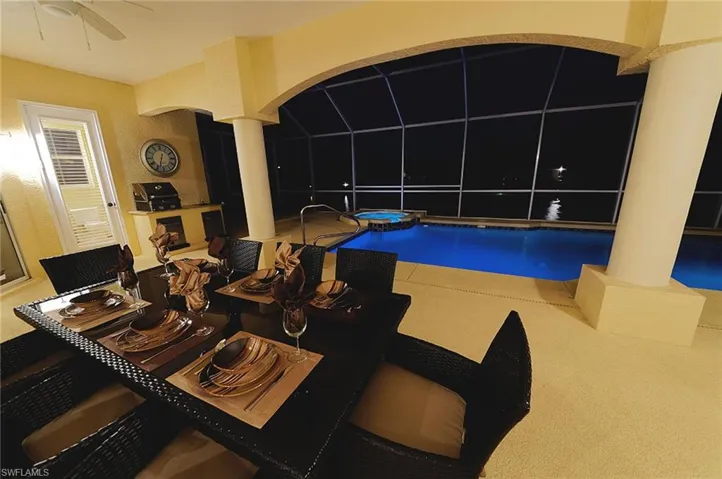 View of swimming pool with ornate columns, a ceiling fan, and a pool with connected hot tub
