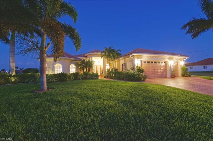 Mediterranean / spanish home featuring a garage, driveway, a lawn, and stucco siding