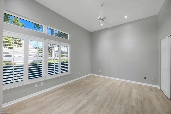 Bright guest bedroom with vaulted ceilings, luxury vinyl flooring, and tropical views.
