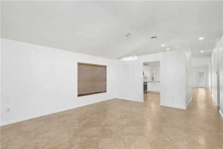 Unfurnished living room with lofted ceiling and a chandelier