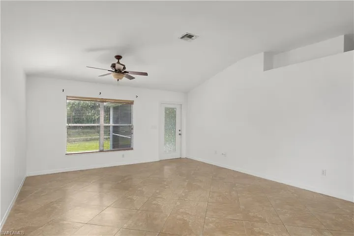Spare room featuring vaulted ceiling, light tile patterned floors, and ceiling fan