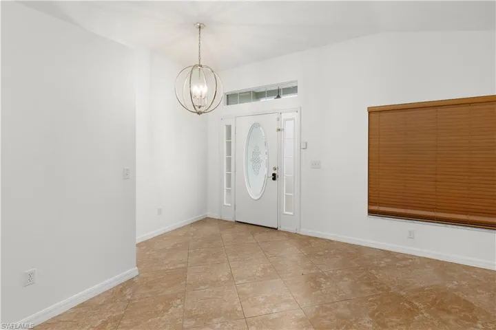 Tiled foyer with vaulted ceiling and an inviting chandelier
