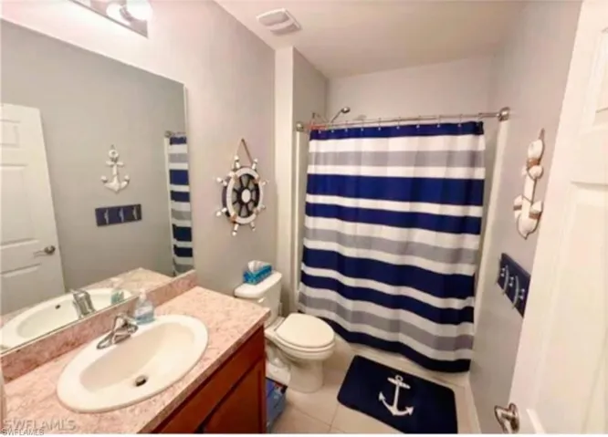 Full bath with vanity, light tile patterned floors, and a shower with curtain