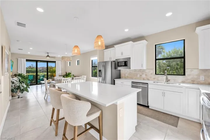 Kitchen with hanging light fixtures, recessed lighting, a center island, white cabinets, and tasteful backsplash