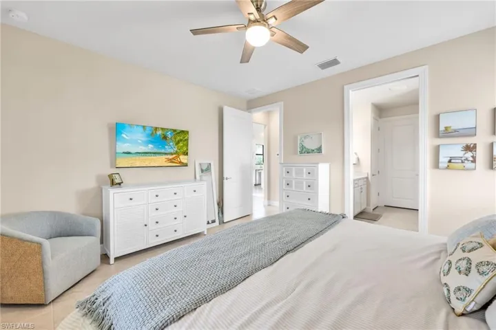 Bedroom with light tile patterned floors, ceiling fan, and connected bathroom
