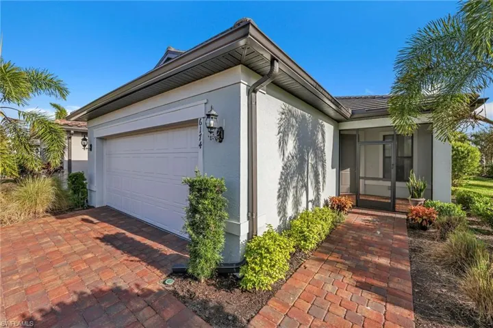 View of side of property with stucco siding, a sunroom, and a garage
