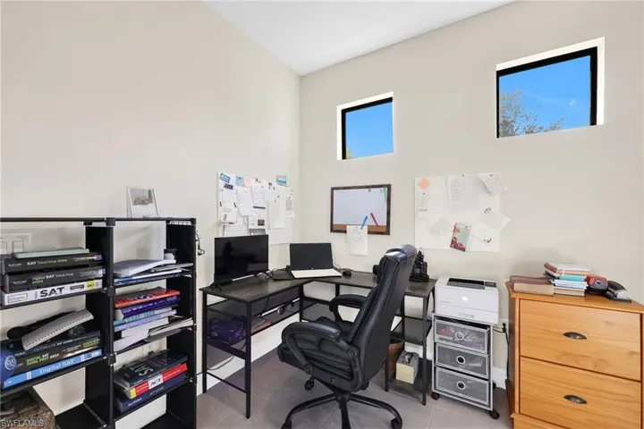 Home office featuring light tile patterned flooring and a towering ceiling