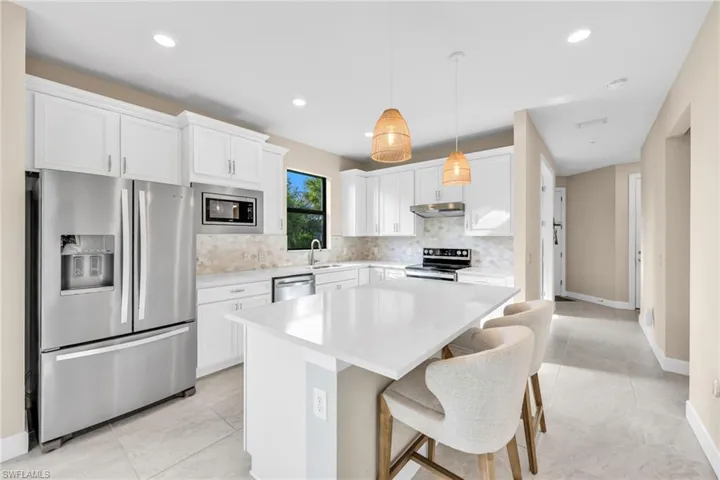 Kitchen with appliances with stainless steel finishes, tasteful backsplash, white cabinets, and recessed lighting