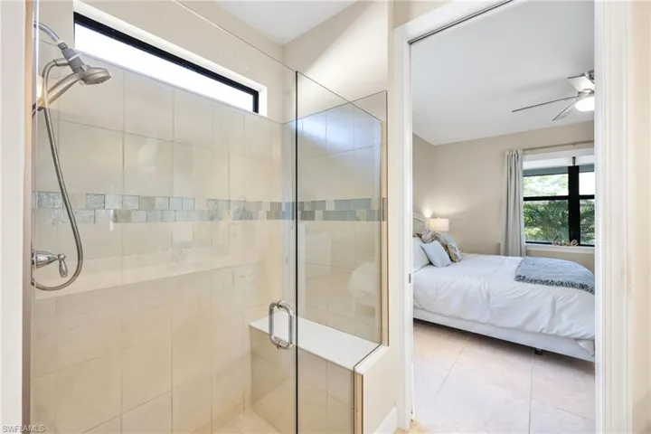 Full bathroom featuring healthy amount of natural light, ensuite bathroom, a shower stall, and tile patterned flooring