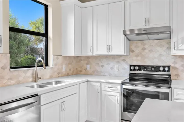 Kitchen with stainless steel appliances, white cabinetry, and backsplash