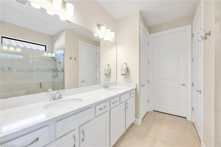 Full bathroom with a stall shower, double vanity, and light tile patterned floors