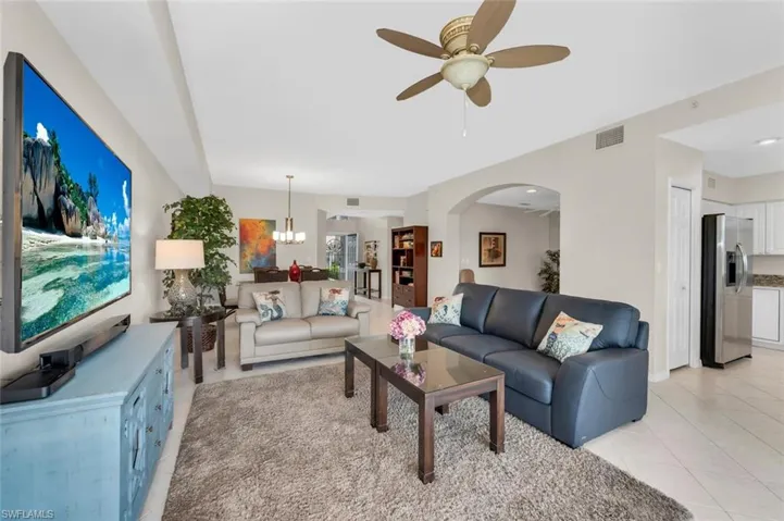 Living room featuring a ceiling fan, light tile patterned flooring, and a chandelier