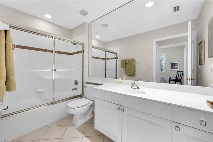 Full bathroom with vanity, enclosed tub / shower combo, tile patterned floors, and recessed lighting