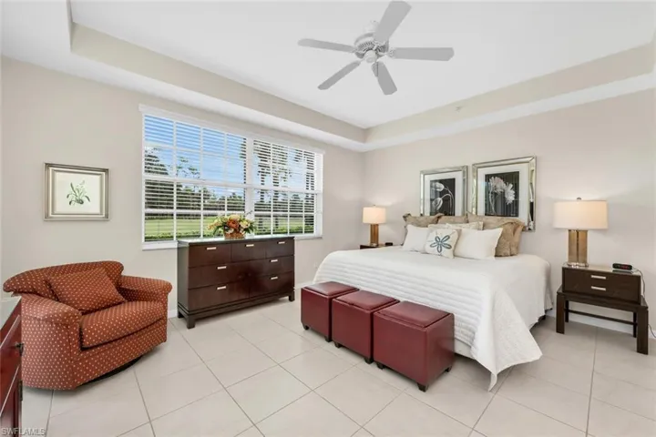 Bedroom featuring a tray ceiling, light tile patterned floors, and ceiling fan