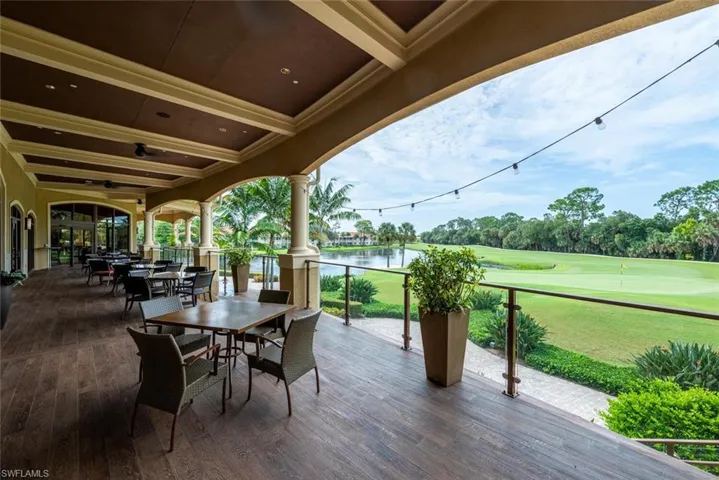 View of community patio featuring view of golf course, outdoor dining area, a water view, and a ceiling fan
