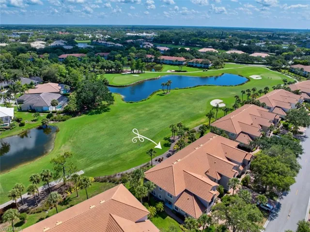 Aerial perspective of condo building with a golf course and lake