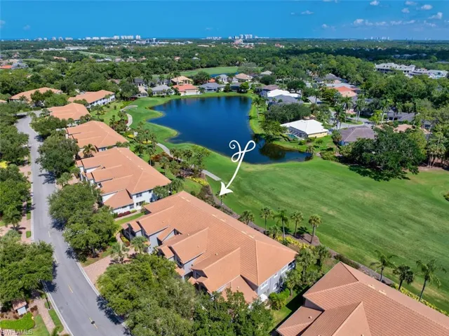 Aerial view of condo building featuring golf course and lake