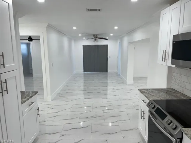 Kitchen with a ceiling fan, white cabinets, stainless steel appliances, crown molding, and recessed lighting
