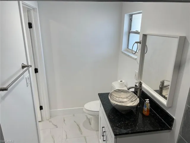 Half bathroom with light marble finish flooring and vanity