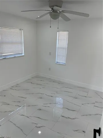 Unfurnished room featuring light marble finish flooring and a ceiling fan