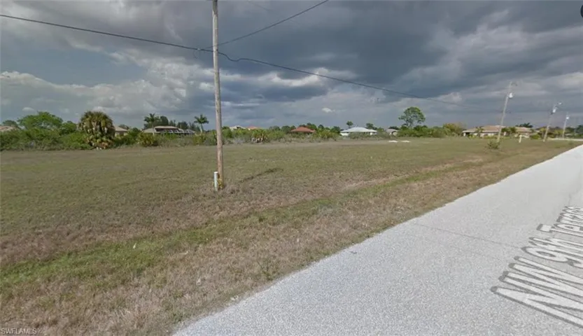 Expansive undeveloped lot with street frontage, featuring a level topography and scattered mature vegetation