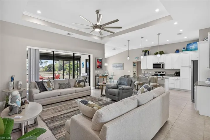 Living room featuring a ceiling fan, recessed lighting, a high tray ceiling, and light tile floors