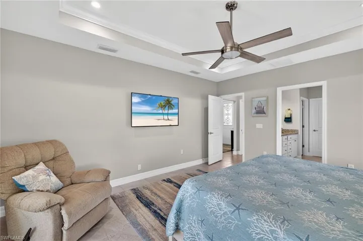 Bedroom with glass sliders access to outside, a ceiling fan, and a raised ceiling