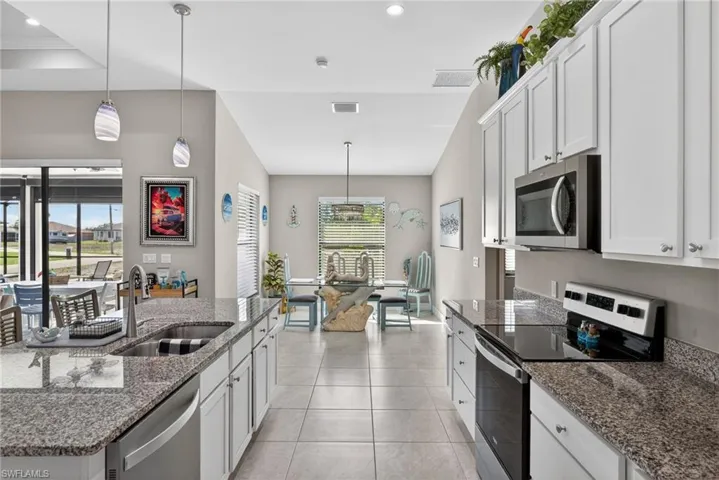 Kitchen with stainless steel appliances, decorative light fixtures, dark stone countertops, and white cabinets