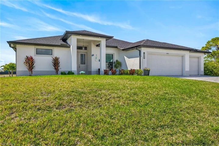 Modern style house featuring a front yard, stucco siding, a 3 car garage, driveway, and a shingled roof