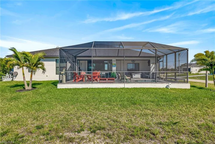 Rear view of house featuring glass enclosure, a sunroom, and a yard