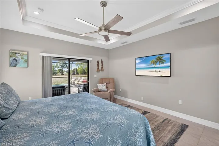 Bedroom with glass sliders access to outside, a ceiling fan, and a raised ceiling