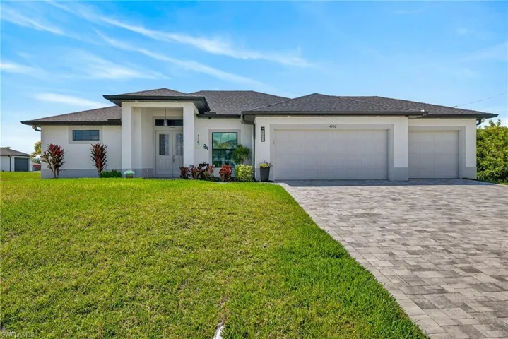 Modern-style house with decorative driveway, stucco siding, an attached garage, roof with shingles, and a front yard