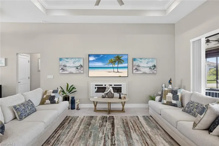 Living room with ceiling fan, high ceilings, and built-in fireplace