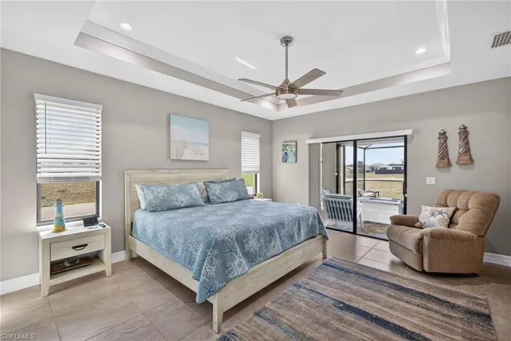 Bedroom featuring access to exterior, ceiling fan, a tray ceiling, and recessed lighting