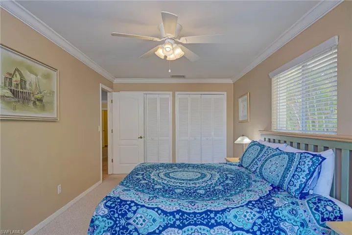 Bedroom with carpet flooring, multiple closets, visible vents, crown molding, and baseboards