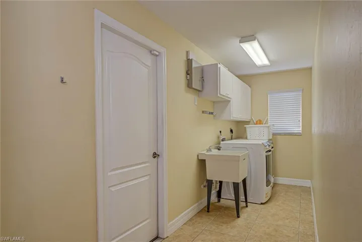 Laundry area with baseboards, cabinet space, washer / clothes dryer, and light tile patterned floors